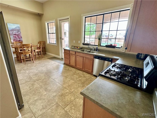 kitchen featuring freestanding refrigerator, a healthy amount of sunlight, dishwasher, and a sink