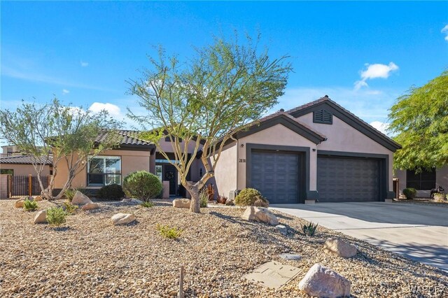 view of front of house with a garage, a tile roof, concrete driveway, and stucco siding