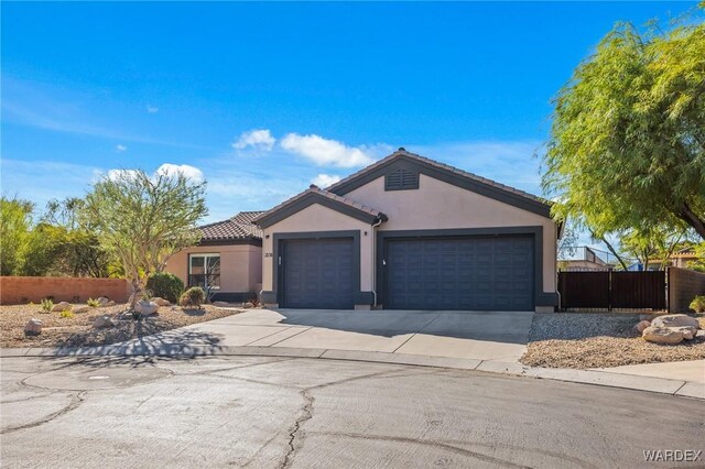 ranch-style house featuring an attached garage, fence, a tile roof, concrete driveway, and stucco siding