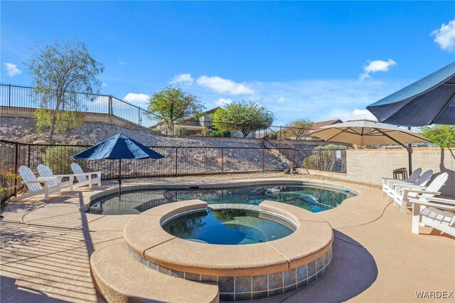 view of swimming pool with a fenced backyard, a pool with connected hot tub, and a patio