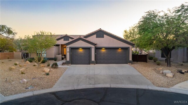 view of front of house with a garage, fence, concrete driveway, and stucco siding