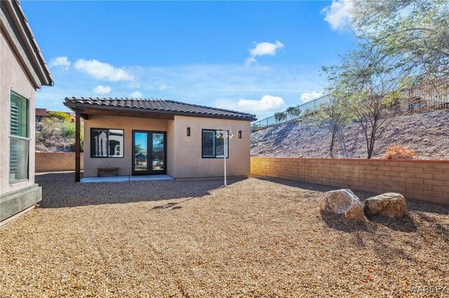 back of property with a tile roof, a patio area, a fenced backyard, and stucco siding