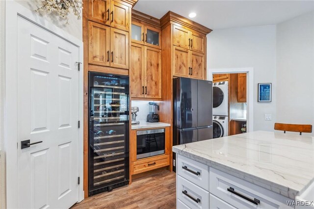 kitchen with wine cooler, glass insert cabinets, white cabinets, stacked washing maching and dryer, and light stone countertops