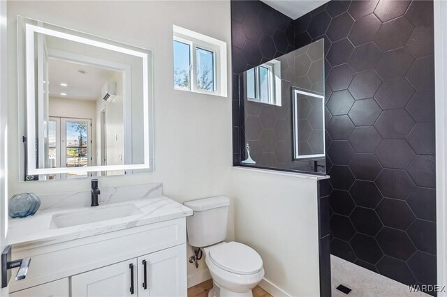 bathroom with toilet, vanity, baseboards, an AC wall unit, and walk in shower