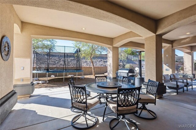 view of patio / terrace featuring outdoor dining space, a trampoline, area for grilling, and fence