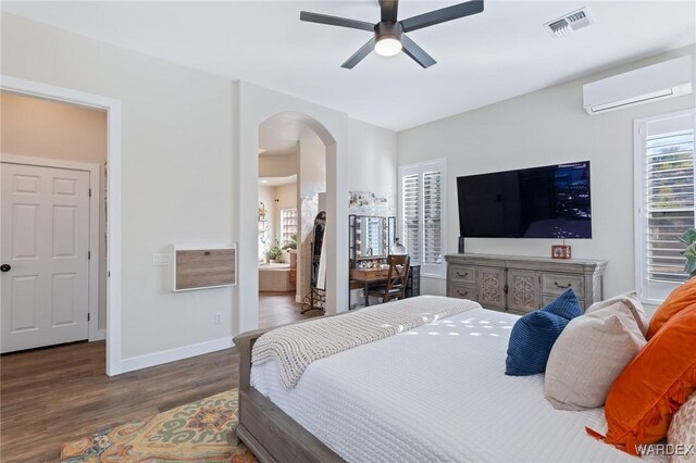 bedroom with baseboards, visible vents, arched walkways, dark wood-style flooring, and a wall mounted AC