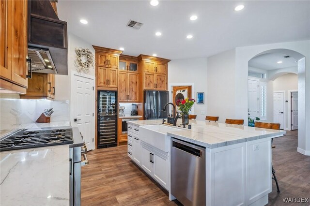 kitchen with visible vents, white cabinets, freestanding refrigerator, dishwasher, and a kitchen bar