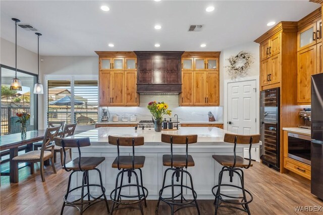 kitchen featuring decorative light fixtures, glass insert cabinets, and custom range hood