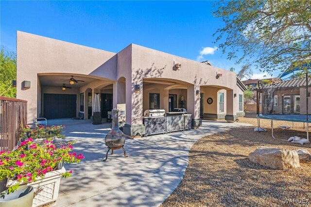 back of house featuring a fire pit, a trampoline, a patio area, and stucco siding