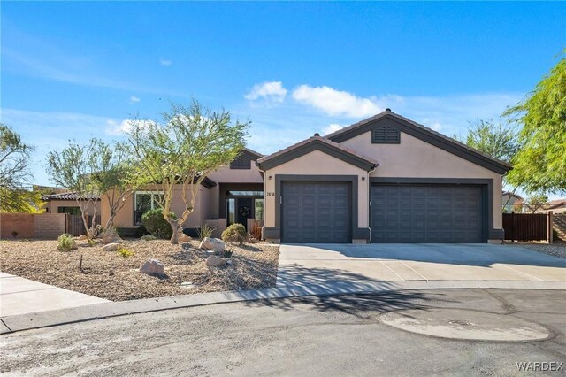 ranch-style home with concrete driveway, an attached garage, fence, and stucco siding