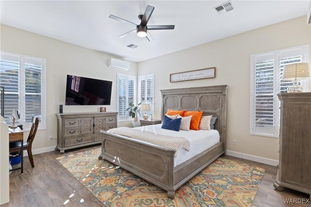 bedroom featuring a wall mounted air conditioner, visible vents, and wood finished floors