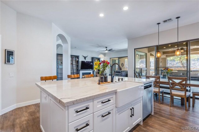 kitchen featuring a sink, white cabinetry, open floor plan, dishwasher, and a center island with sink