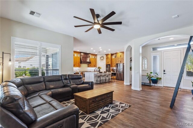 living area with baseboards, visible vents, arched walkways, dark wood-style flooring, and recessed lighting