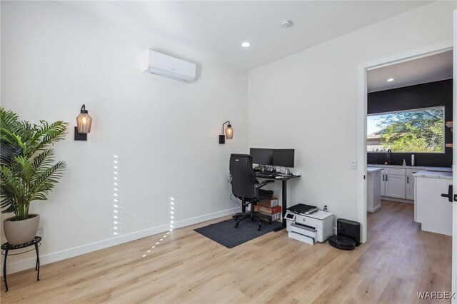 home office with light wood finished floors, a wall mounted AC, recessed lighting, and baseboards