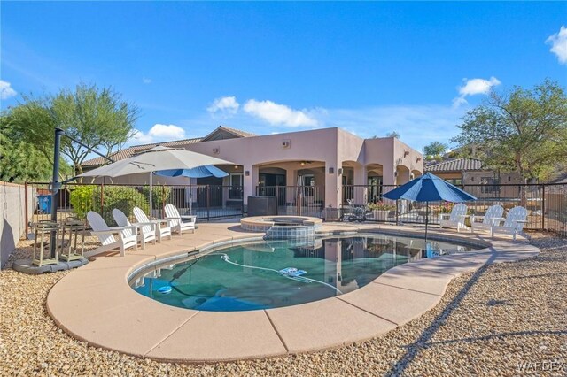 view of pool with a pool with connected hot tub, fence, and a patio