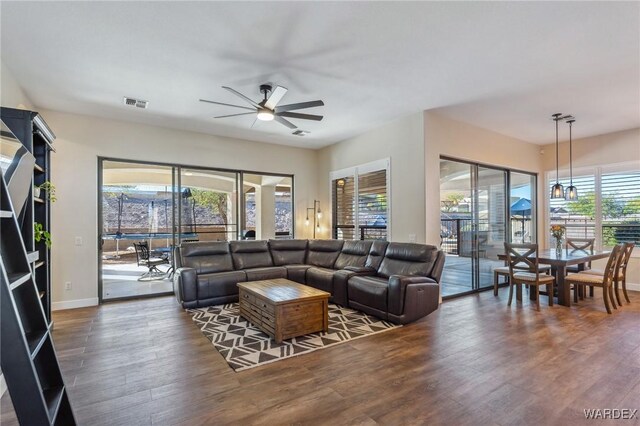 living room featuring ceiling fan, dark wood-style flooring, visible vents, and baseboards