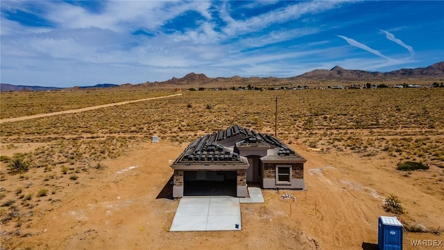 entry to storm shelter featuring a rural view, a mountain view, and view of desert
