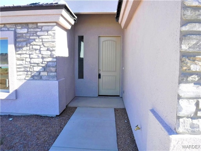 doorway to property featuring stone siding and stucco siding