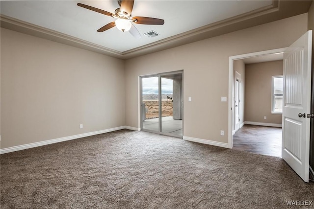carpeted spare room featuring visible vents, baseboards, a ceiling fan, and plenty of natural light