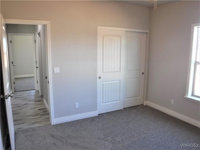 unfurnished bedroom featuring a closet, baseboards, and carpet