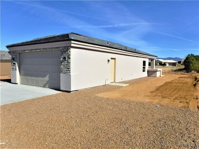 view of property exterior with roof mounted solar panels, driveway, a garage, and stucco siding