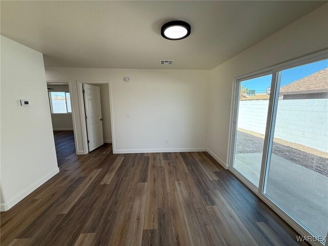 spare room with visible vents, dark wood finished floors, and baseboards