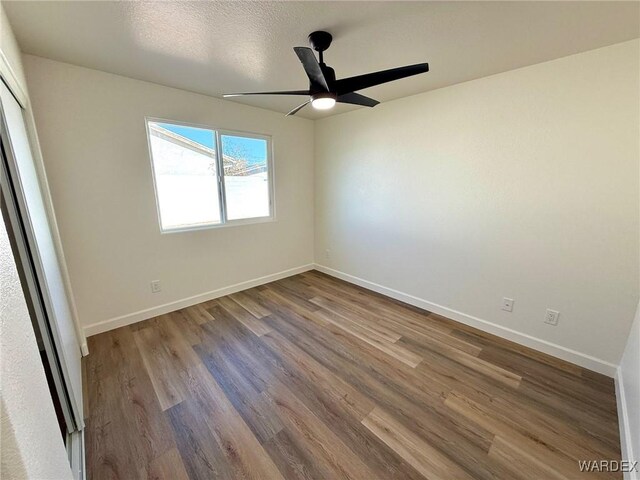 empty room with a ceiling fan, baseboards, and wood finished floors