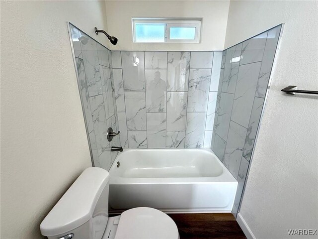 bathroom featuring shower / bath combination, a textured wall, toilet, and wood finished floors