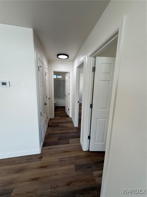 hall with dark wood finished floors and baseboards