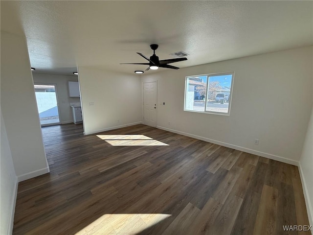 spare room with plenty of natural light, dark wood finished floors, visible vents, and baseboards