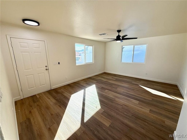 interior space featuring ceiling fan, dark wood-style flooring, visible vents, and baseboards