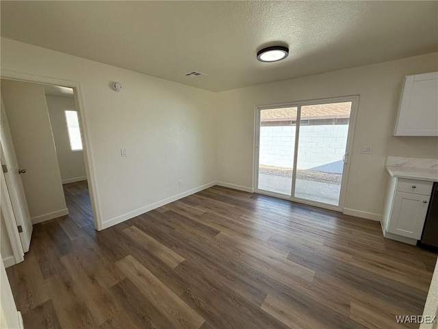 interior space with baseboards, dark wood finished floors, visible vents, and a healthy amount of sunlight