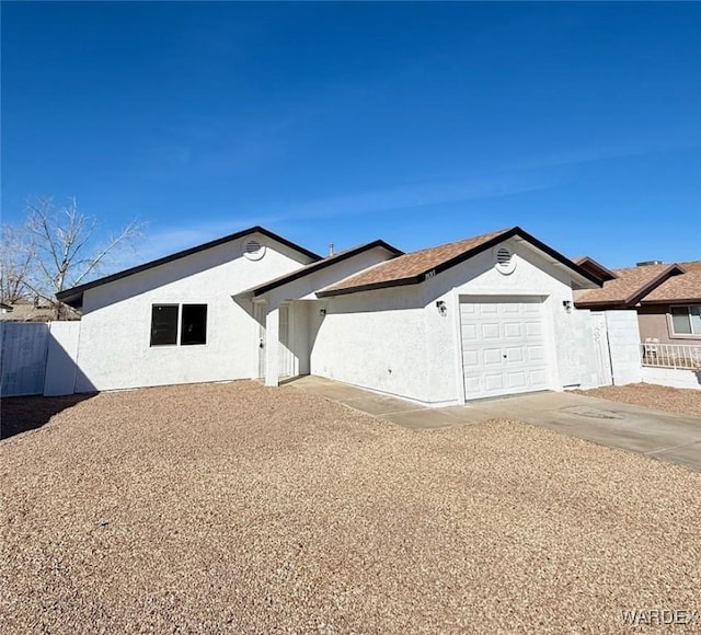 ranch-style house with driveway, fence, an attached garage, and stucco siding