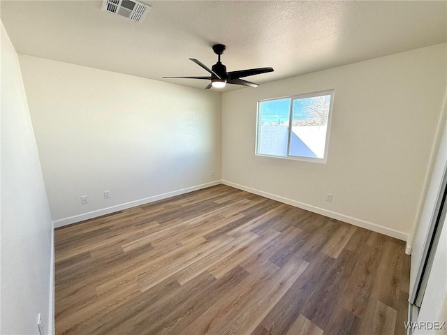 spare room featuring ceiling fan, wood finished floors, visible vents, and baseboards