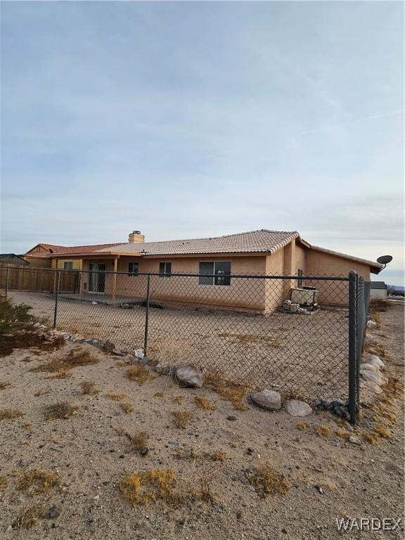 view of side of property featuring a tiled roof, fence, and stucco siding