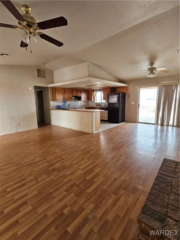 unfurnished living room featuring lofted ceiling, visible vents, a textured ceiling, and wood finished floors