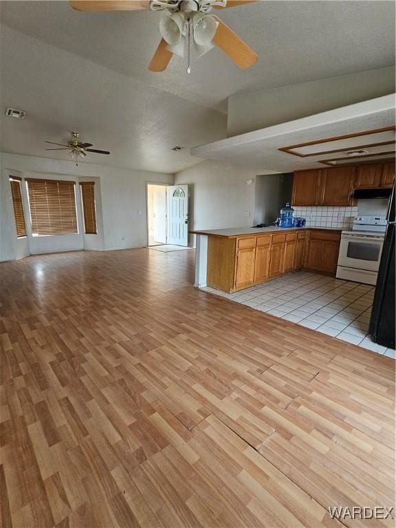 kitchen with brown cabinets, white range with electric cooktop, light countertops, visible vents, and open floor plan