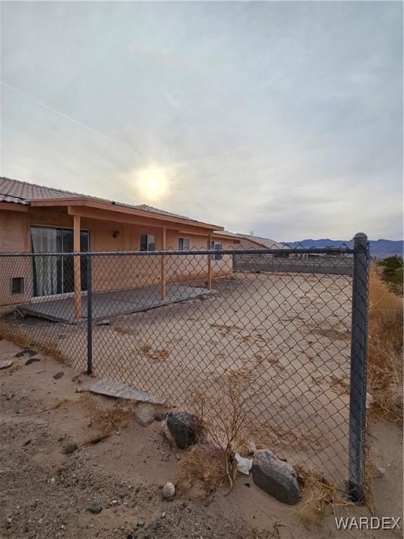 view of side of home with fence, a mountain view, and stucco siding