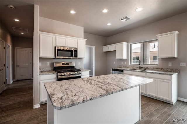 kitchen with visible vents, appliances with stainless steel finishes, white cabinets, and a center island