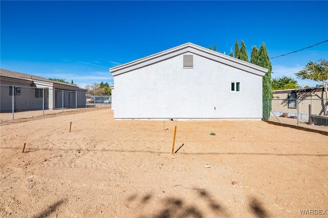 view of side of property featuring fence and stucco siding