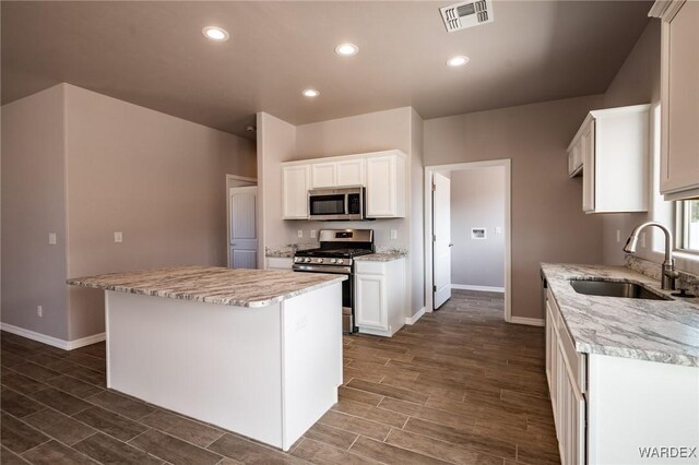 kitchen featuring white cabinets, a kitchen island, visible vents, and stainless steel appliances