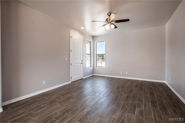 spare room featuring dark wood finished floors, a ceiling fan, and baseboards