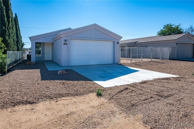 view of front of property featuring an attached garage, fence, concrete driveway, and an outbuilding