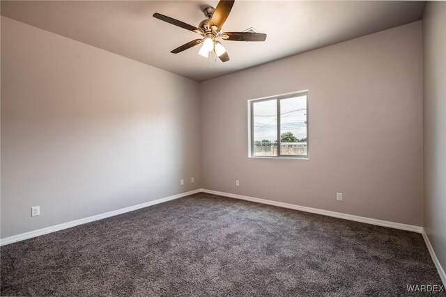 unfurnished room with ceiling fan, baseboards, and dark carpet