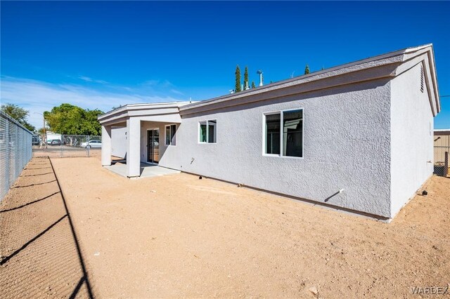 rear view of property featuring a patio, fence, and stucco siding