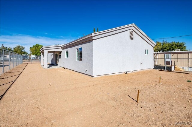 rear view of property with fence and stucco siding