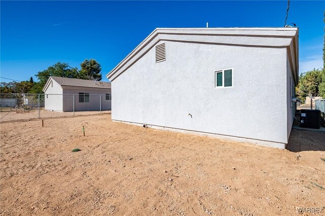 view of side of home featuring cooling unit, fence, and stucco siding