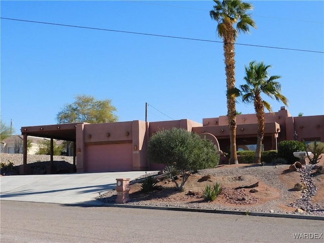 pueblo-style home with driveway, a garage, and stucco siding