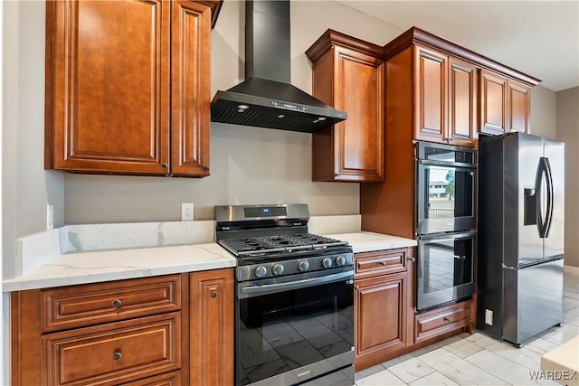 kitchen with wall chimney range hood, light stone counters, stainless steel appliances, and brown cabinetry