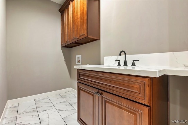 bathroom with marble finish floor, vanity, and baseboards